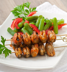 Fried mussels with onions on skewers c garnish of green beans an