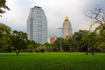 Fototapeta premium Tropical trees and lawn with skyscrapers in the background in