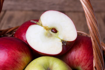 Fresh red apples in basket over wooden background