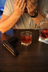 Man crying with gun and alcohol