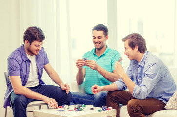 happy three male friends playing poker at home
