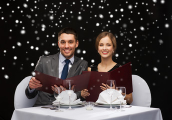 smiling couple with menus at restaurant