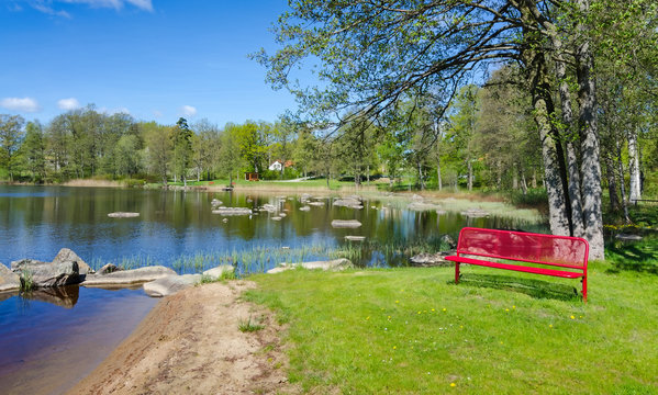Spring lake panorama landscape with symbolic red bench
