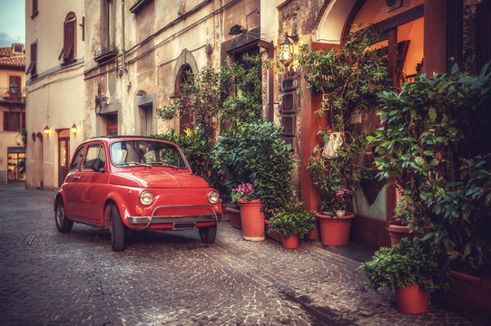 Fototapeta Stary, kultowy samochód zaparkowany na ulicy przy restauracji, w