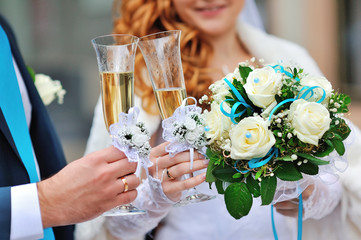 Two wedding glasses with champagne in hands of bride and groom