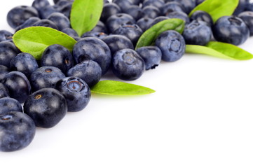 Several whole blueberries with leaves isolated on white corner