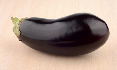 Studio shot of single aubergine eggplant on bright wooden table