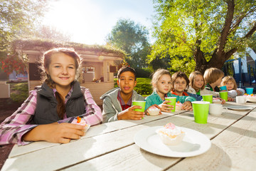 Many children sit at table with bright cups