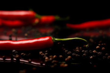 Studio shot of chilli peppers and black pepper on black