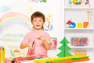 Positive small boy holding scissors and carton