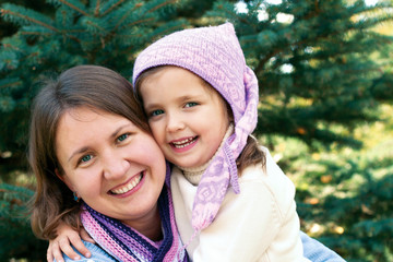 Obraz premium Happy family hugging near a Christmas tree on the street
