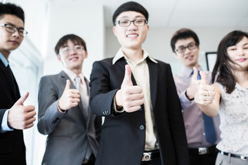 Business team holding their thumbs up