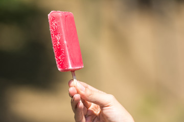 Girl Hand Holding Pink Ice Cream On Stick