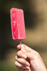 Girl Hand Holding Pink Ice Cream On Stick