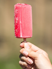Girl Hand Holding Pink Ice Cream On Stick