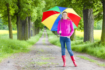 woman wearing rubber boots with umbrella in spring alley