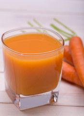 Fresh-squeezed carrot juice on wooden background 