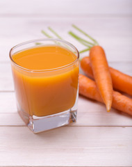 Fresh-squeezed carrot juice on wooden background 