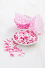 colored sugar hearts and paper baking dishes, vertical, close-up