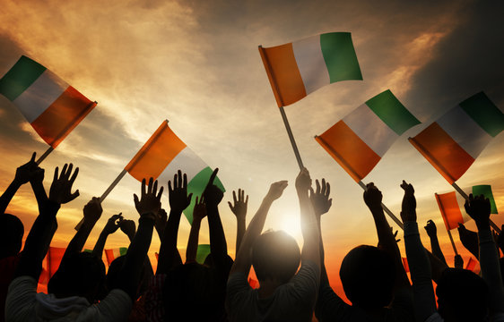 Silhouettes Of People Holding Flag Of Ireland