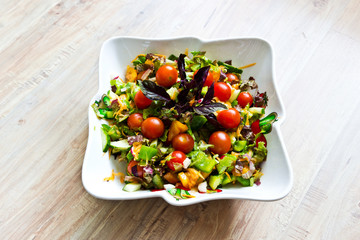 Fresh vegetable salad with basil leaves in ceramic bowl