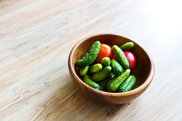 Fresh vegetables: cucumbers and tomatoes in wooden dish