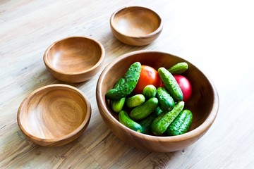 Fresh vegetables: cucumbers and tomatoes in wooden dish