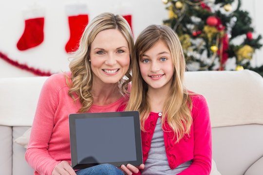 Festive mother and daughter showing tablet screen - Powered by Adobe
