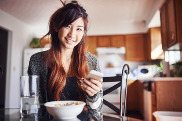 asian teen girl with smart-phone at breakfast - Powered by Adobe