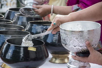 puts food offerings in a Buddhist monk's alms bowl