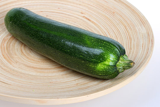 Fresh zucchini vegetable on wooden plate