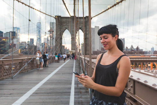 Young Woman Using Smart Phone on Brooklyn Bridge