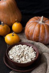 Obraz na płótnie Canvas Pumpkins and a bowl with toasted pumpkin seeds, wooden spoon