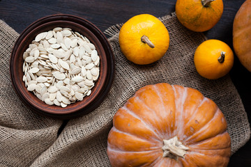 Pumpkins and a bowl with toasted pumpkin seeds, wooden spoon