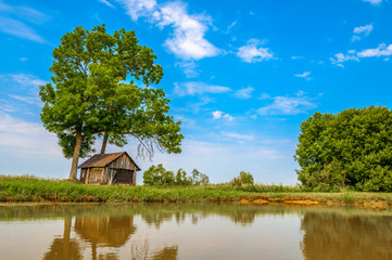 Fototapeta na wymiar Old house near lake with blue sky and tree on background
