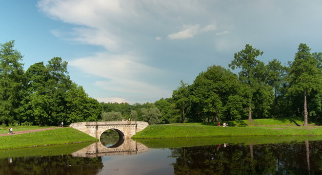 A bridge over a river in the park with clouds. Time lapse.