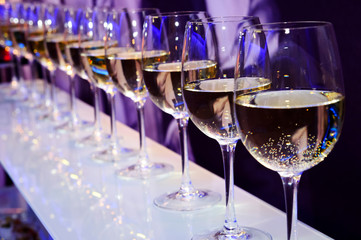 Nightclub glasses with white wine lit by festive lights