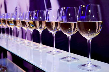 Nightclub glasses with white wine lit by festive lights