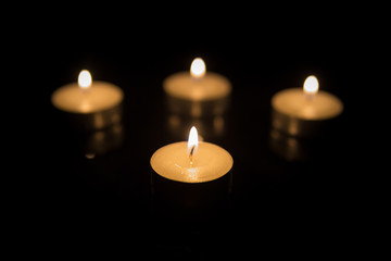 Four Tea Candles with Reflection on Black