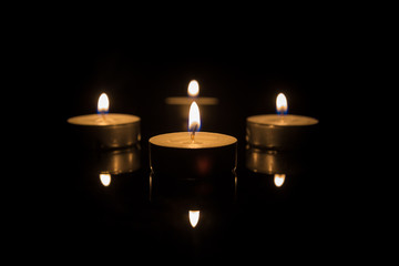 Four Tea Candles with Reflection on Black