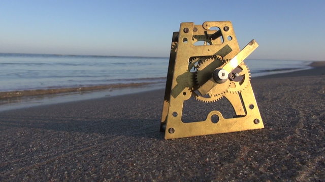 Time and ocean concept. Clock brass gear on sand