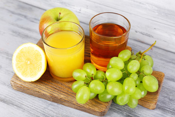 glasses of juice with fresh fruits on grey wooden table