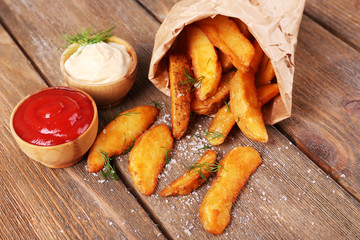 Homemade fried potato in paper bag, on wooden background © Africa Studio
