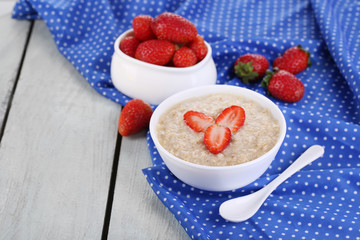 Tasty oatmeal with strawberry on table close-up