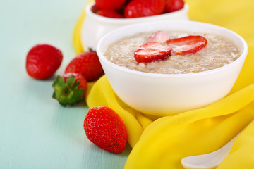 Tasty oatmeal with strawberry on table close-up