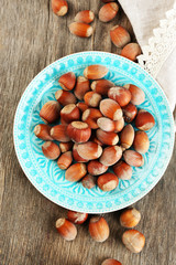 Hazelnuts on plate on wooden background