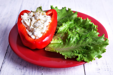 Stuffed pepper and lettuce on plate on wooden background