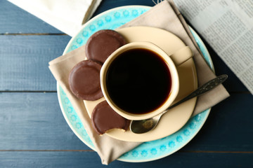 Cup of coffee with tasty cookies on color wooden background