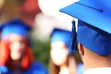 Graduate students wearing graduation hat and gown, outdoors