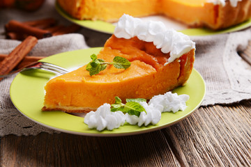 Piece of homemade pumpkin pie on plate on wooden background